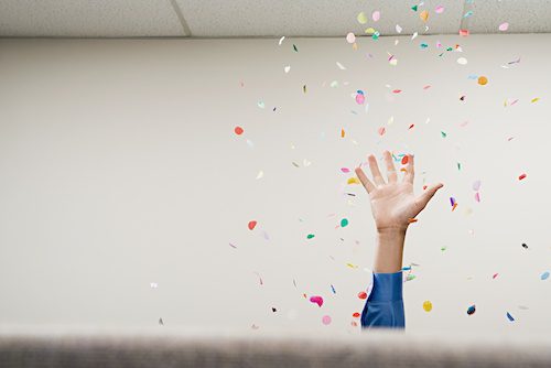 Photo of hand throwing confetti into the air